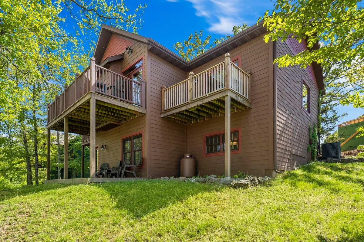 The exterior of the home highlighting two balconies overlooking a green lawn and surrounded by trees. The inviting balconies hint at spaces perfect for morning coffee or stargazing, seamlessly connecting indoors and outdoors.