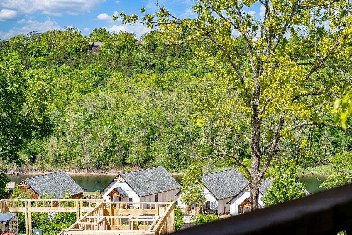 An exterior image featuring a tranquil river bordered by trees and nearby houses, evoking the serenity and beauty of the local area—perfect for activities like fishing, hiking, and picnicking mentioned in the section.