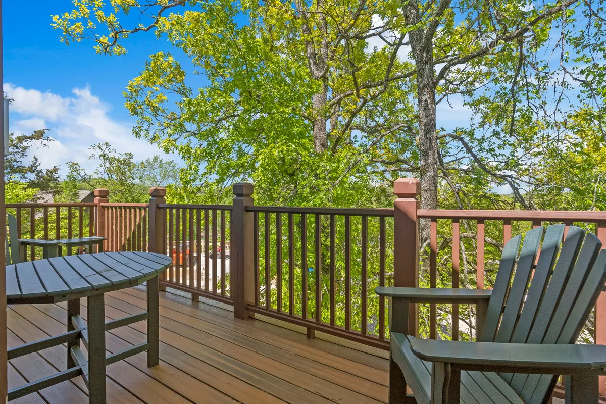 An inviting wooden deck surrounded by green trees and furnished with comfortable outdoor seating. The peaceful setting suggests the ideal spot for al fresco dining, morning coffee, or sunset suppers while enjoying the tranquil wooded views.